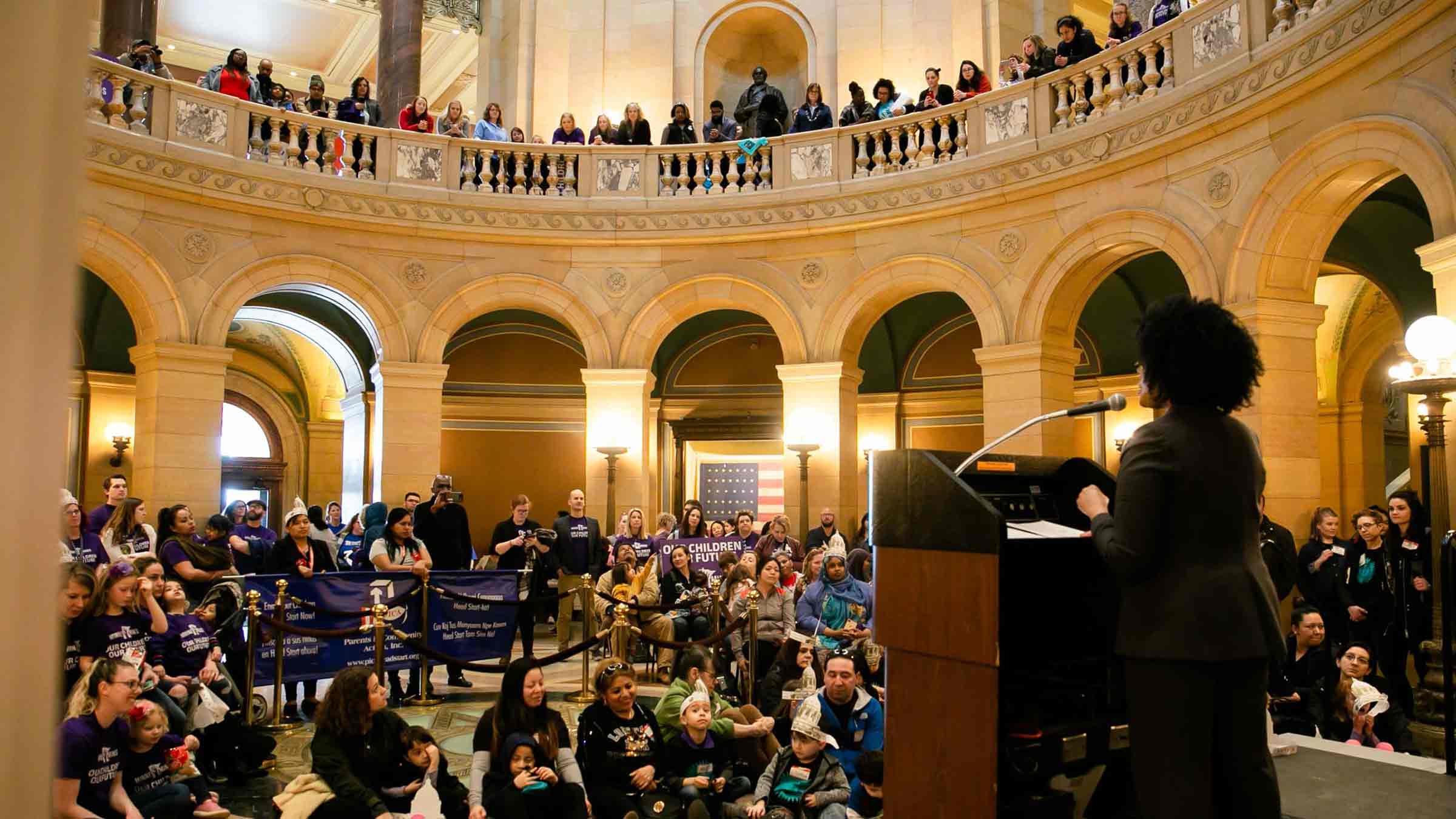 A speaker stands in the Minnesota state capital building addressing a group of early childhood education advocates